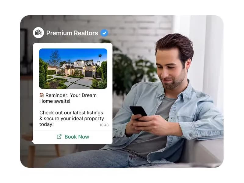 Home buyer on a sofa reading a WhatsApp message from a verified realtor showing a new property listing with a Book Now button